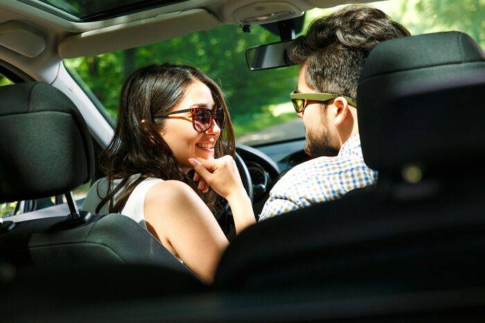 Couple wearing sunglasses smiling inside a car during a casual date, capturing wild dating experiences moments.