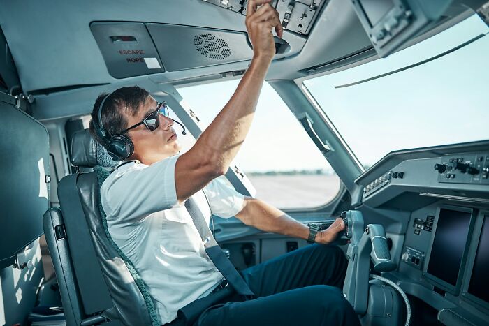 Pilot in airplane cockpit adjusting controls, illustrating underrated plane perks to enhance your flight experience.