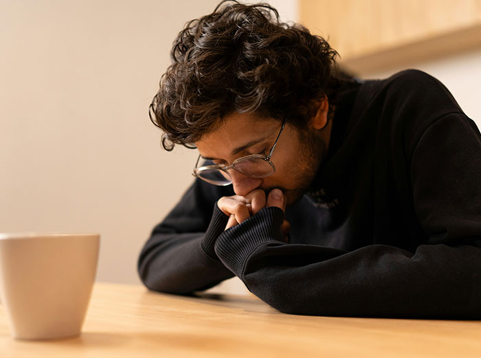 Man looking upset and thoughtful at a gift, reflecting on emotions in a quiet indoor setting.