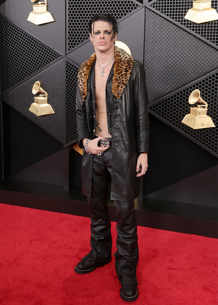 Person wearing a black leather coat with leopard collar and pants on the red carpet showing 2016 Grammys fashion trends.