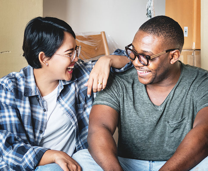 Couple laughing together in casual clothes, highlighting a guy trying to warn another couple about having kids.
