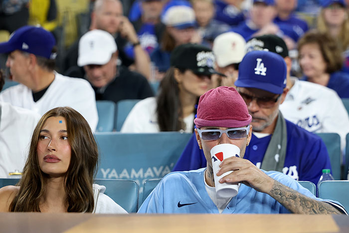 Justin and Hailey Bieber attending a sports event with a tense moment observed by lip readers.