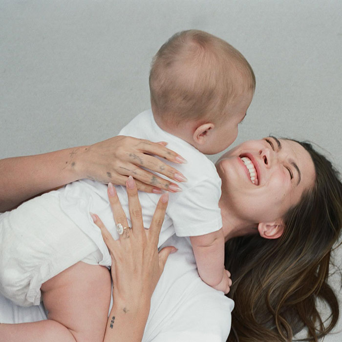 Hailey Bieber smiling while holding her toddler son, highlighting a pathological liar claim met with public skepticism.