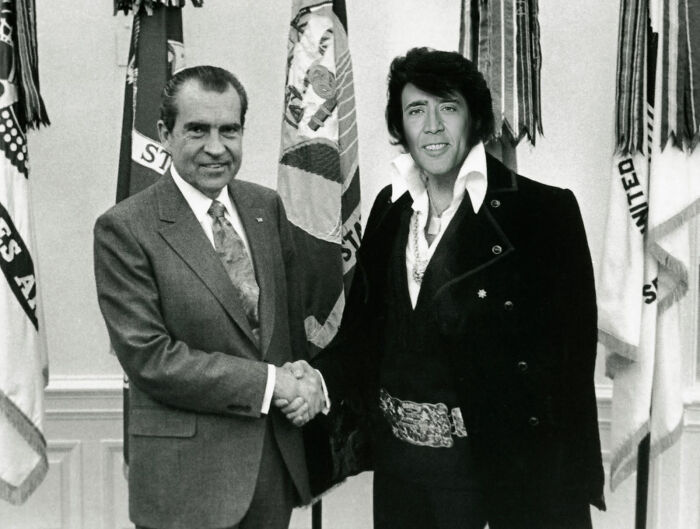 Vintage photo of two men shaking hands with one edited to have an unhinged and wild appearance, showcasing Photoshop effects.