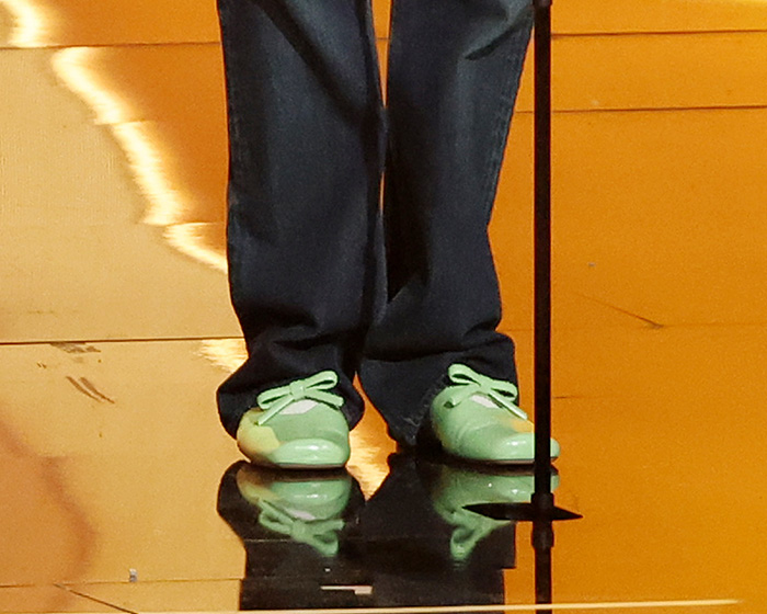 Close-up of Harry Styles wearing shiny green shoes and dark pants during an on-stage appearance at the 2026 Grammys.