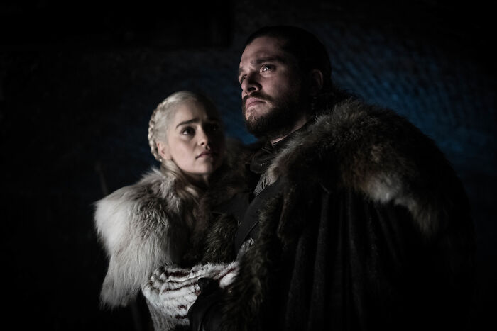 Kit Harington and Sophie Turner as Jon Snow and Daenerys Targaryen in Game of Thrones wearing fur costumes in a dark scene. Kit Harington and Sophie Turner as Jon Snow and Daenerys Targaryen in Game of Thrones wearing fur costumes in a dark scene.