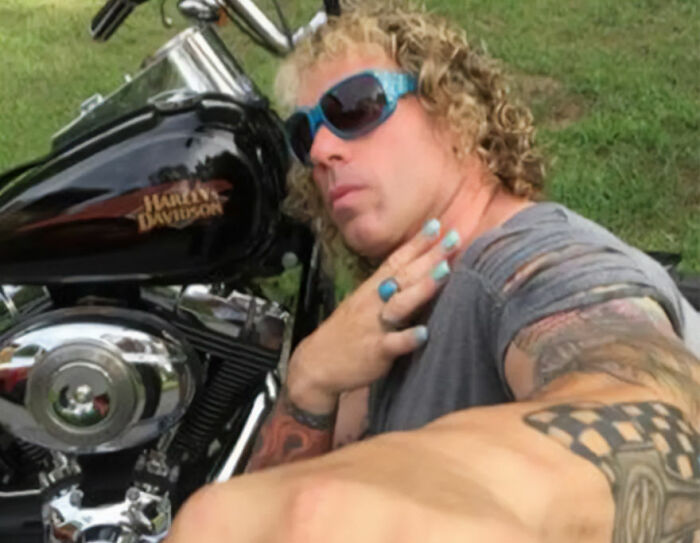 Transgender mom Roberta Esposito wearing sunglasses, posing next to a Harley Davidson motorcycle outdoors.