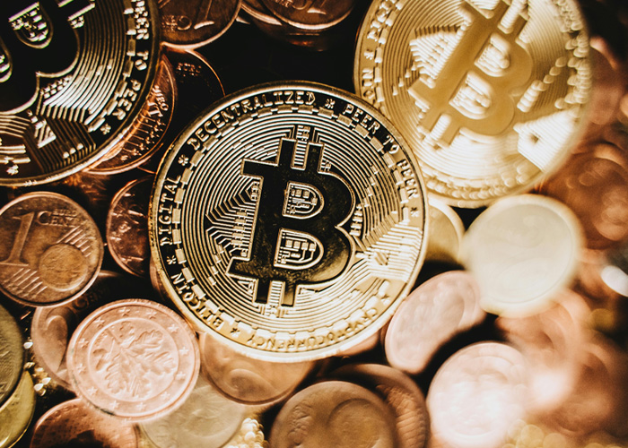 Close-up of physical Bitcoin coins stacked among various other coins, symbolizing cryptocurrency and exchange control.