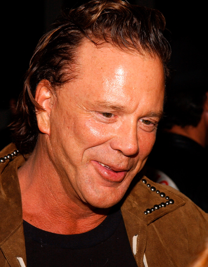Mickey Rourke smiling at an event showing his natural look without dramatic cosmetic procedures.