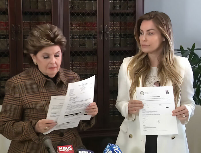 Hugh Hefner's widow holding documents during a press conference discussing claims about the Playboy founder.