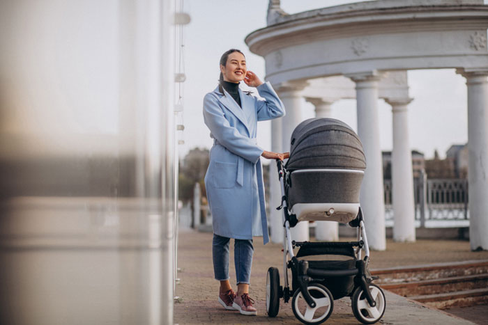 Mom with stroller outdoors near columns, representing mom-to-be surprised by stroller gifted without discussion.