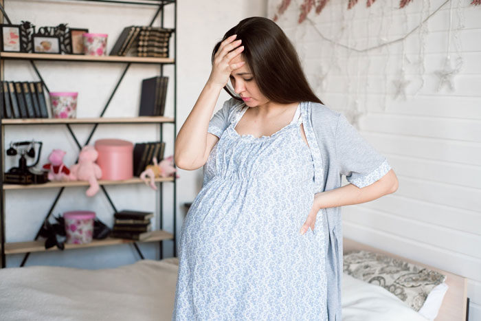 Pregnant mom standing in empty nursery, looking shocked and stressed, discovering stroller was gifted without discussion.