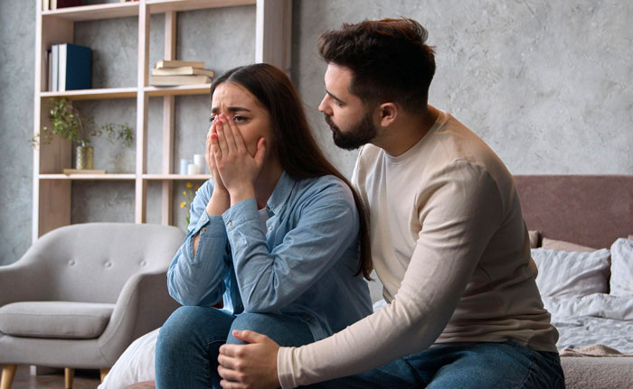 Woman upset after uncovering gym affair, man seeks freedom to explore outside of marriage in a tense living room setting.