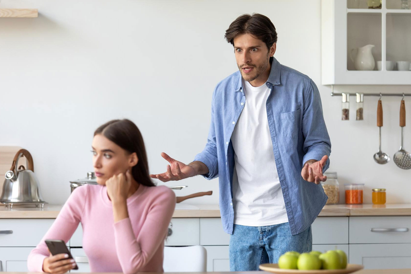 Wife gives up social life for family and work, upset as husband angrily confronts her in kitchen setting.