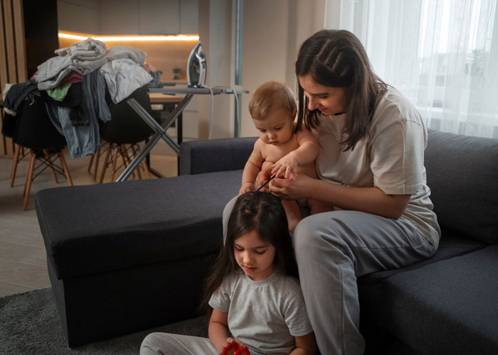 Wife giving up social life for family and work, sitting with children at home in casual clothes on a couch.