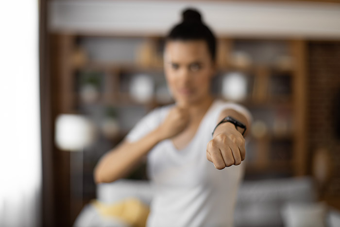 Woman showing a clenched fist in a tense moment, symbolizing conflict and divorce papers in a home setting.