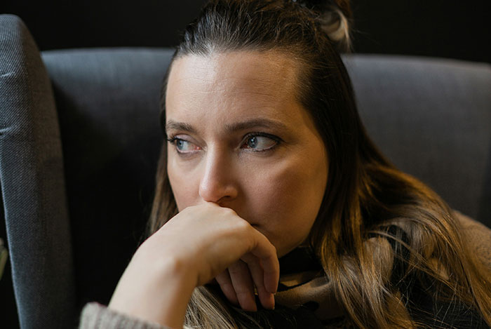 Pensive woman sitting in a chair, reflecting on struggles with husband who keeps leaving and coming back.