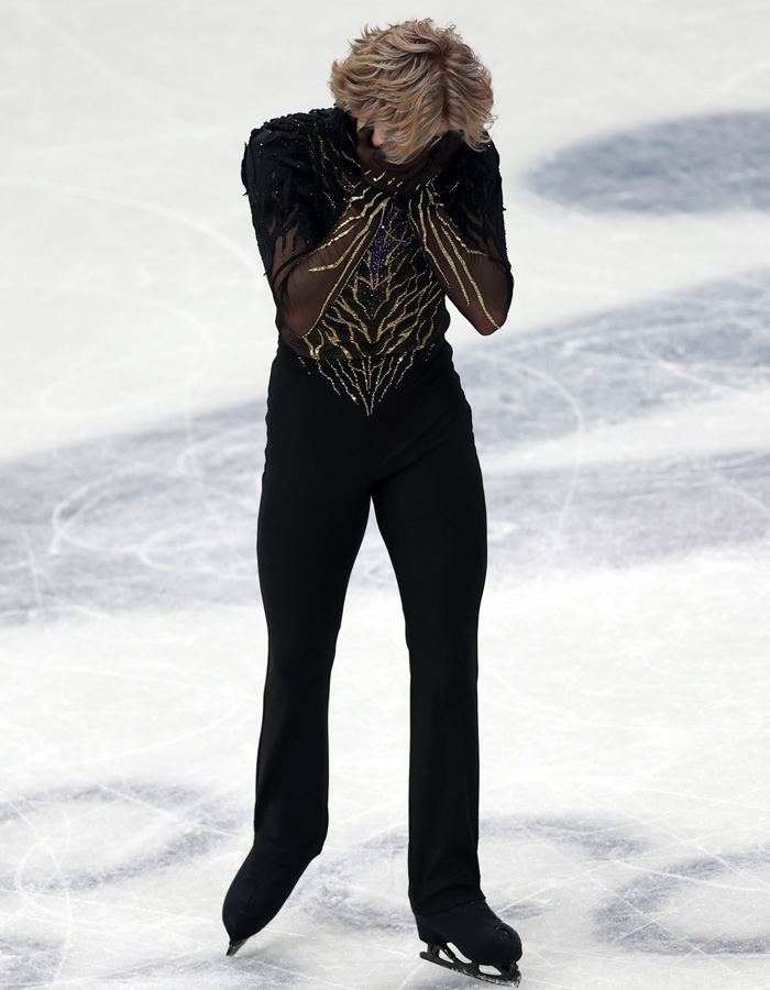 Ilia Malinin on ice wearing black and gold costume covering face after tough Olympic showing during figure skating event