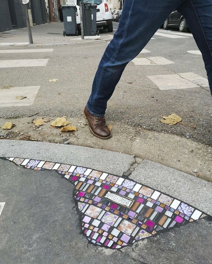 Person stepping near a street pothole decorated with colorful tiles, showcasing reality glitched through a clever illusion.