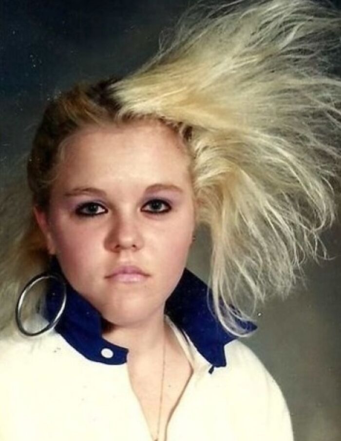Young woman with an iconic 80s hairdo featuring voluminous, teased blonde hair and bold makeup.
