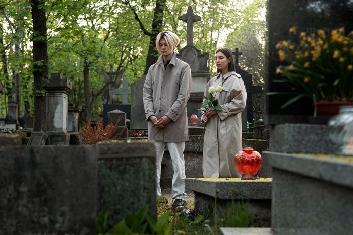 Two young adults visiting late wife's grave during a private family tradition at a quiet cemetery. Two young adults visiting late wife's grave during a private family tradition at a quiet cemetery.
