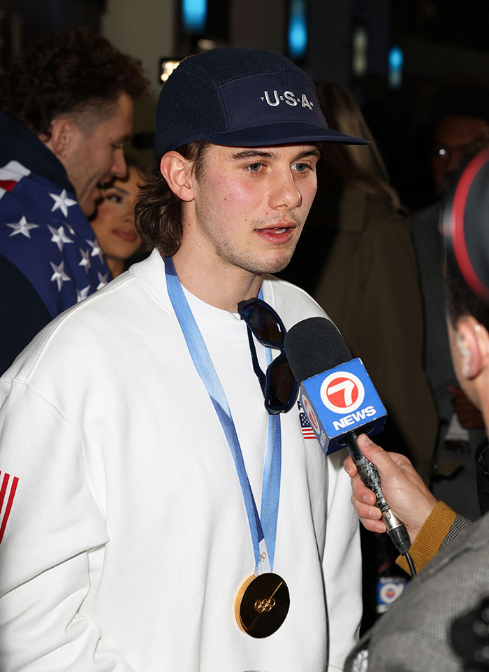 US Olympics hero Jack Hughes wearing medal and USA cap, speaking to news reporter during interview. US Olympics hero Jack Hughes wearing medal and USA cap, speaking to news reporter during interview.