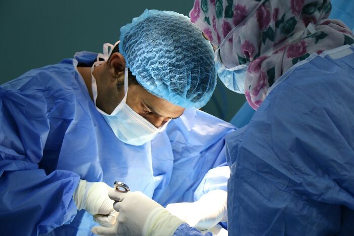 Surgeons in blue scrubs and masks working under bright lights, illustrating toxic workplace moments in healthcare settings.
