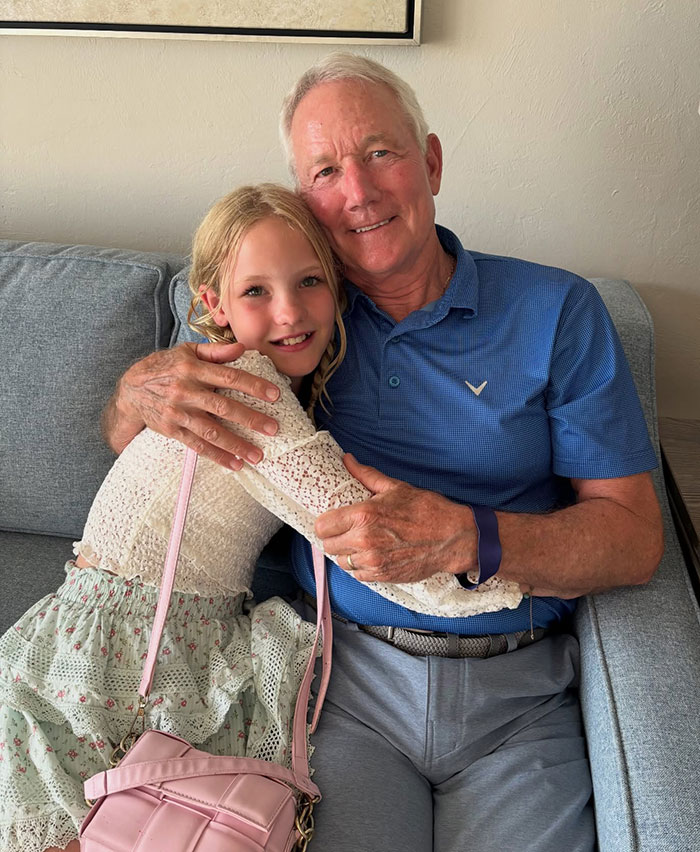 Elderly man and young girl hugging on a couch, reflecting on James Van Der Beek’s final post breaking hearts.