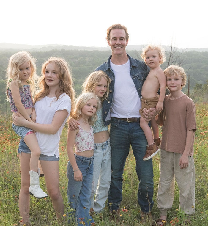 James Van Der Beek smiling outdoors with six children in a field of wildflowers during golden hour.