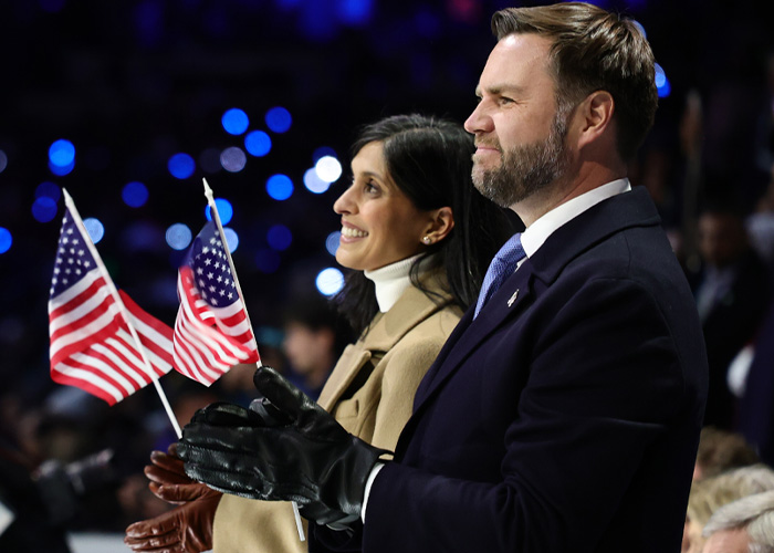 JD Vance clapping with a woman, both holding small American flags at the Winter Olympics inauguration ceremony