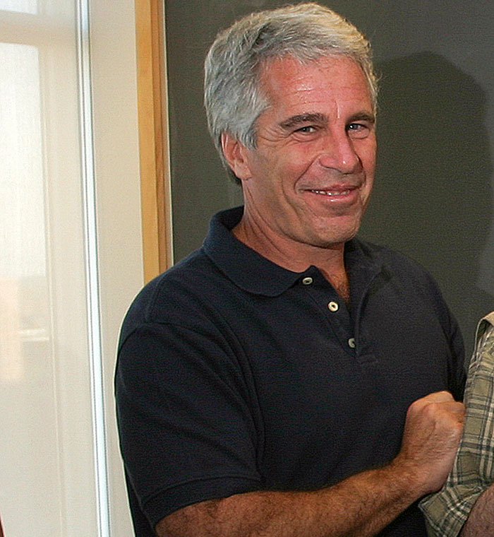 Man with gray hair and navy polo shirt smiling indoors, related to Timoth&eacute;e Chalamet Epstein files publicist claims topic