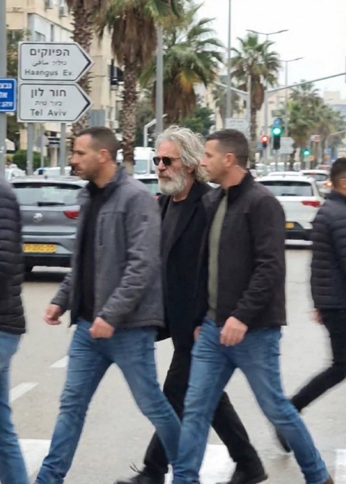 Man with gray hair and beard wearing sunglasses walking on street amid others, linked to viral Epstein Fortnite theory.