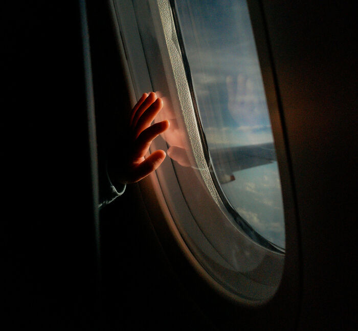 Toddler&rsquo;s hand touching airplane window, illustrating Southwest seating dispute over refusing to pay extra.