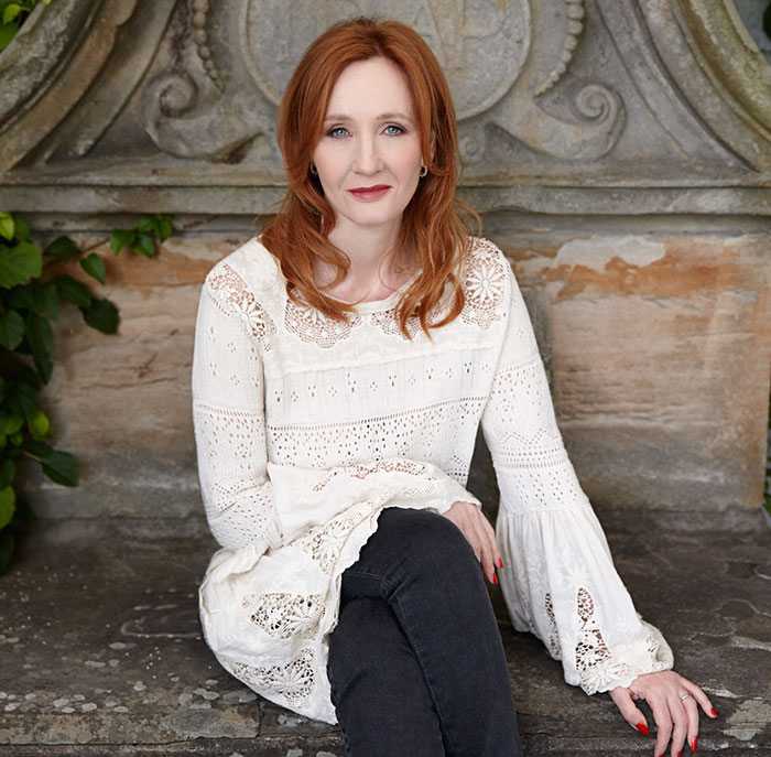 J.K. Rowling sitting outdoors in a white lace top and black pants, addressing Jeffrey Epstein accusations in a serious tone.