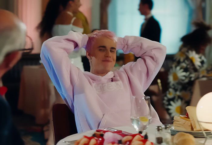 Justin Bieber relaxing at a dinner table scene from the Yummy music video linked to Epstein theory by fans.