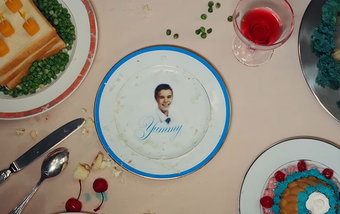 Plate with Justin Bieber's image and the word yummy surrounded by various partially eaten foods and a red drink.