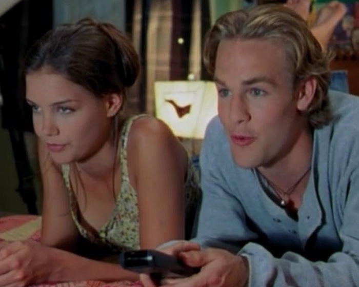 Katie Holmes and James Van Der Beek lying down together in a scene from their TV show, honoring late costar.