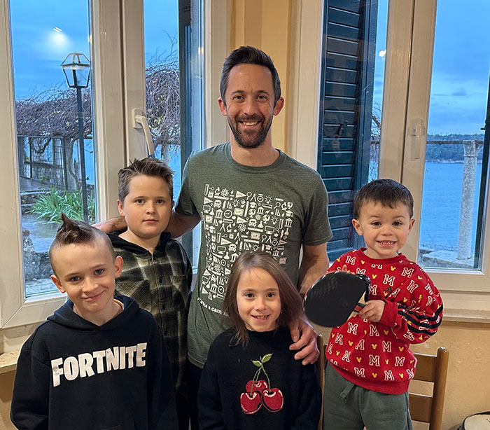 Man with four kids smiling indoors, illustrating four missing kids returned to dad after foreign orphanage separation.