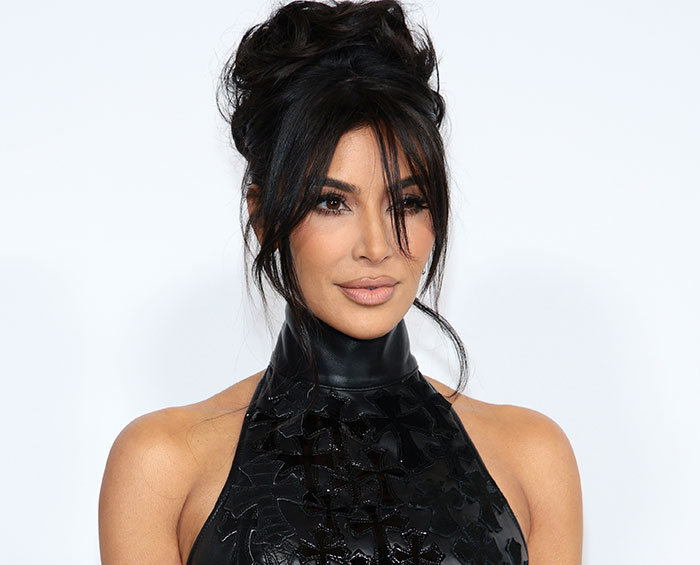 Kim Kardashian posing confidently in a black high-neck outfit, highlighting body language expert analysis of controlled moves.