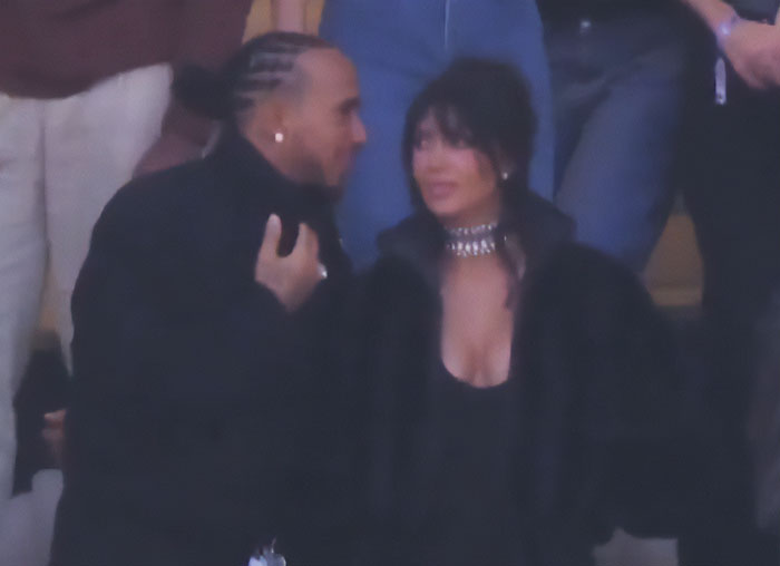 Lewis Hamilton and Kim Kardashian engaged in conversation, showing tightly controlled body language during a public event.