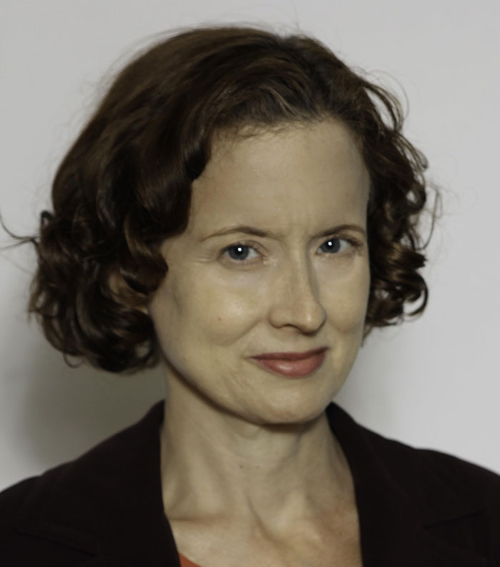 Actress from Grey's Anatomy with short curly hair, posing against a plain background for a portrait photo.