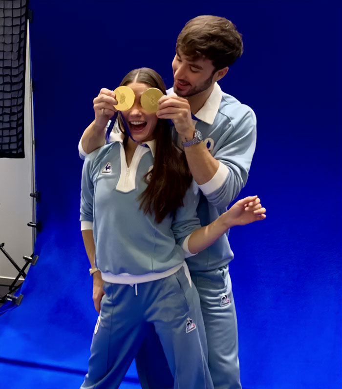 French skater celebrating with a partner, holding gold medals, amid Olympics cheating scandal and suspicious win.