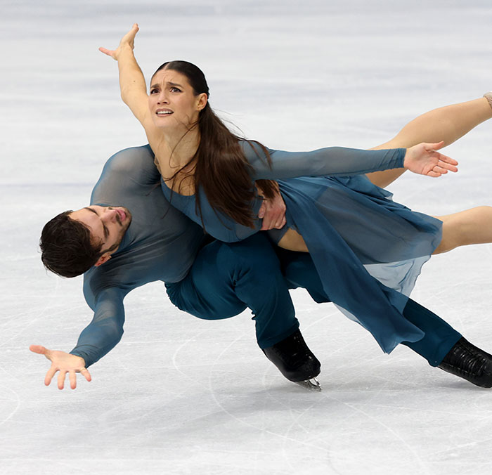 French skater performing a complex lift during ice dance routine amid Olympics cheating scandal discussions.