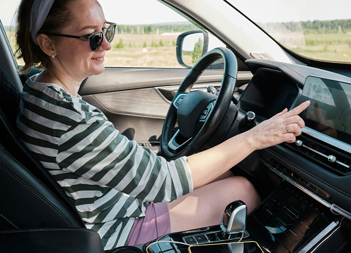 Woman in sunglasses inside car, interacting with the dashboard touchscreen, illustrating divorce lawyers' haunting stories.