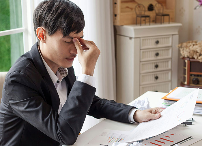 Divorce lawyer in a suit stressed while reviewing messy case files at a desk in a bright office setting.