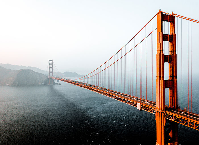 Golden Gate Bridge at sunrise with clear sky and calm water, symbolizing travel and airport situations.