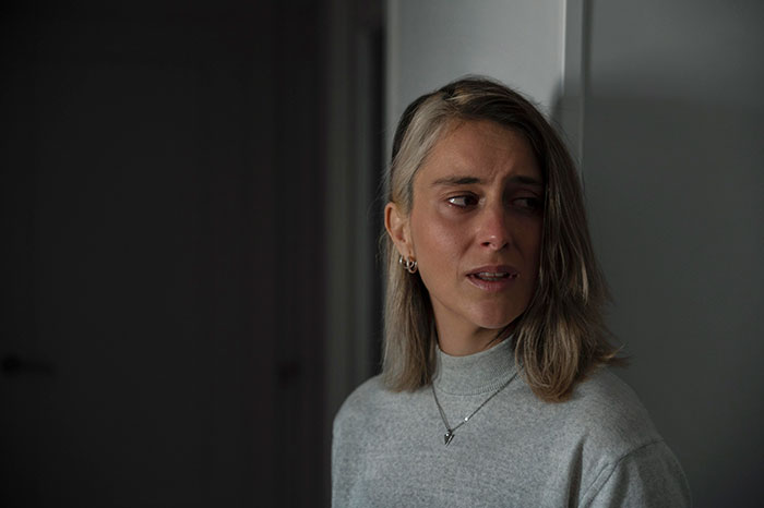 Young woman with a worried expression in dim light, reflecting confusion about her partner being pregnant in a lesbian couple situation.