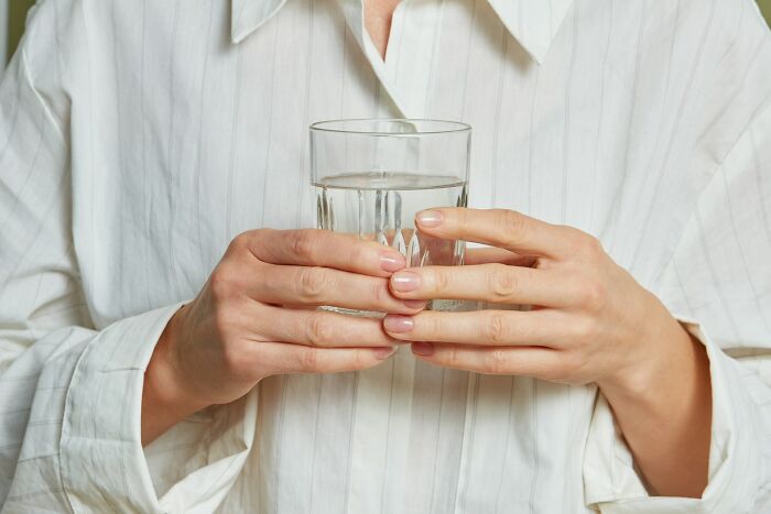 Person wearing a white shirt holding a glass of water, illustrating strange things people witnessed that made them question everything.