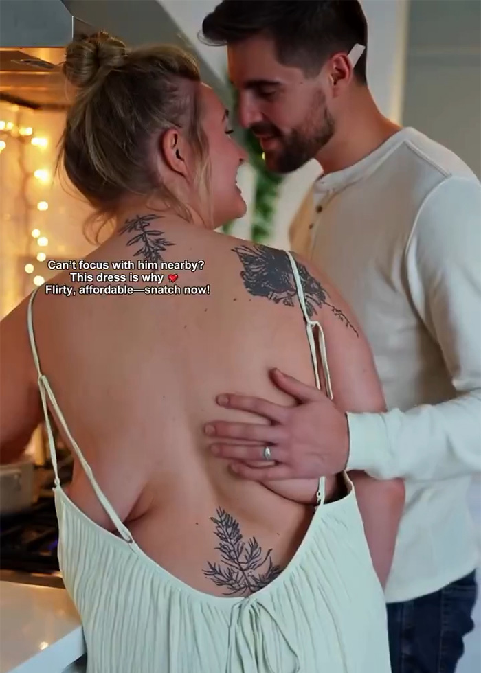 Woman wearing a low-cut dress with tattoos on her back, embraced by a man in a white long-sleeve shirt in a cozy kitchen setting.