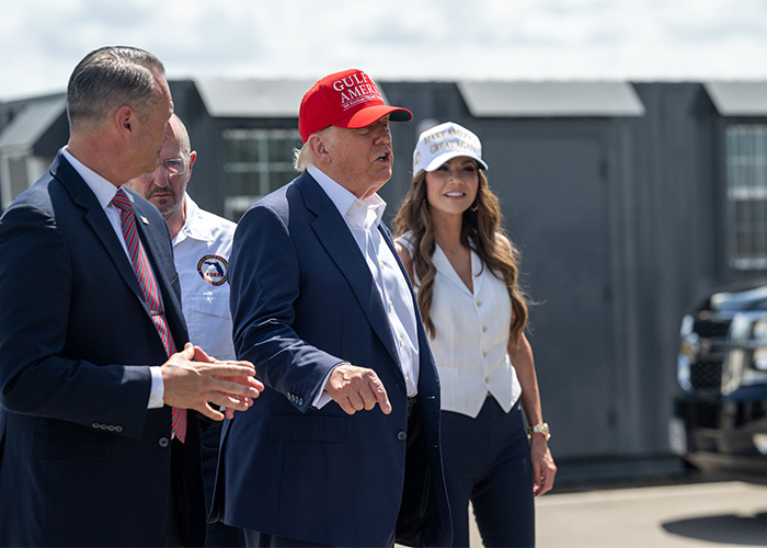 Group including MAGA influencer wearing red hat, outdoors near vehicles, related to detention and deportation topics by ICE.